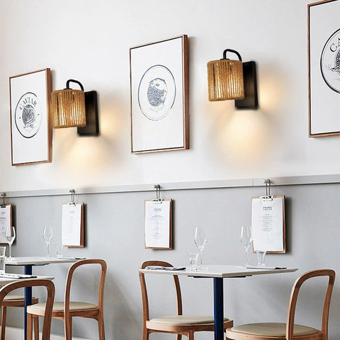 Boho Rattan Wall Sconce With Hemp Rope in rustic modern cafe setting with framed art on walls, cozy warm vibe ambience