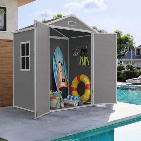 Spacious 6x4 Outdoor Storage Shed With Floor For Bikes Tools And Gear, Resin Plastic Garden Shed, gray with open doors by pool.