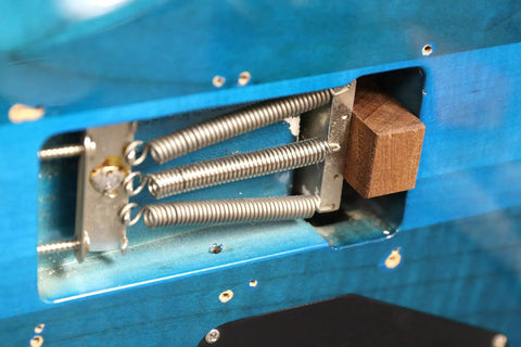 Hella Solid Floating Tremolo Setup Blocks For Quick Guitar Tuning And Deck Leveling Zero Hassle Premium Luthier Gear Strat Style Bridge Stabilizer Wedges, close-up of mahogany wedge and springs in a guitar tremolo cavity.
