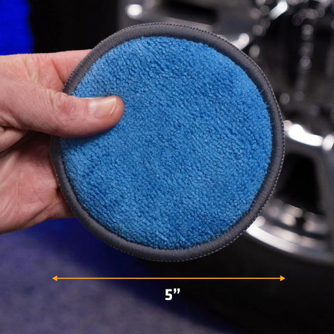 Hand holding blue microfiber pad, size 5 inch, for smooth wax application, part of Four Pack Five Inch Blue And Gray Microfiber Polishing Pads
