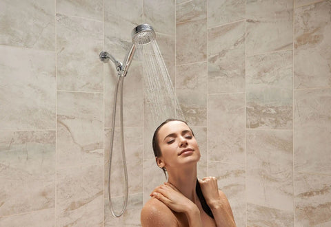 Woman enjoying Caldwell 4.25-Inch 5-Function Handheld Shower With Bracket And 60-Inch Hose Chrome Finish in tiled bathroom.