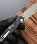Close-up of a Folding Knife With 14C28N Steel Blade And Carbon Fiber Handle Go To EDC Knife With Pocket Clip, held by gloved hand.