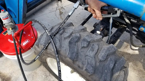 Pneumatic Grease Pump For 25-50Lb Pails, 40:1 Ratio Up To 4,000 PSI connected to tractor tire during lubrication.