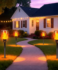 Lit Solar Torch Lights Outdoor With Realistic Flickering Flame 96 LED High Brightness 43 Inch Tall along a garden pathway