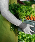 Gardener wearing long gardening gloves with cut resistant sleeves and anti slip nitrile coated palms holding a box of vegetables.