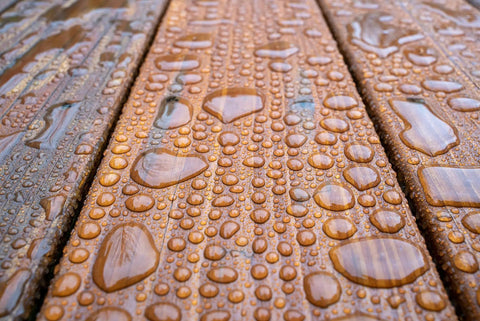 Close-up of water droplets on wood showing All In One Wood Stain And Sealer For Outdoor Wood Projects Semi Transparent Waterproof Finish In Cedar Tone Protects All Wood Types From Moisture Prevents Graying Extends Exterior Wood Life 1 Gallon protection