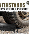 Rugged Waterproof Case With Airtight Gasket Seal And Foam Interior under large vehicle tire on rocky terrain