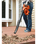 Person using Cordless Leaf Blower With Battery And Charger, 40V Max PowerCommand on deck to clear leaves, 120 MPH peak air speed.