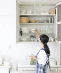 Woman organizing kitchen cabinet shelves