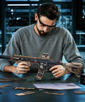 3D Puzzle For Adults M416 Replica Wooden Mechanical Puzzle Model For Home Decor Desk Ornament Gift For Teens 14 Plus And Adults With Precise Fit Pieces That Click Into Place And A Dope Desk Showpiece For Collectors. man assembling wooden M416 replica rifle puzzle at desk