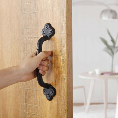 Hand holding Rustic Gate Handle 9 Inch Cast Iron Barn Door Handle on wooden door, black finish, indoor use.