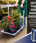 Person using Heavy Duty Foldable Push Cart Dolly with 330 lb capacity for transporting potted plants in a garden setting.