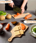 Two bamboo cutting boards on a gray counter; one with a handle slices carrots, crackers arranged on the other.
