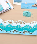 Beach Wave Metal Cutting Dies Set For Scrapbooking And Card Making displayed on a desk with beach-themed craft supplies