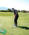 Golfer using Putting Cup With Flag Indoor Golf Hole Practice Kit on grass field, showing accurate short game skills.