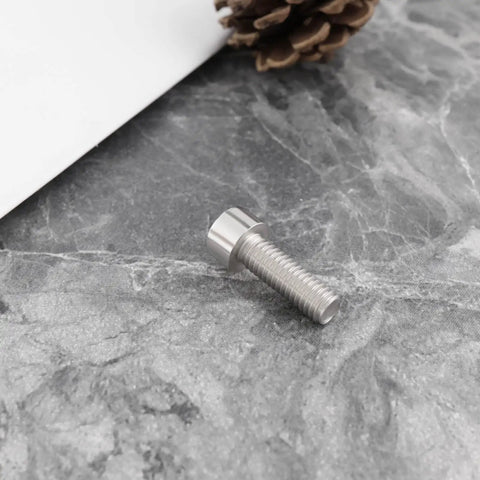 Close-up of a 4Pcs Bike Crank Arm Pinch Clamp Bolt 304 Stainless Steel M6x18mm on a stone surface, part of a replacement kit.