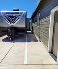 Driveway with RV parked beside a brown house, showing concrete surface