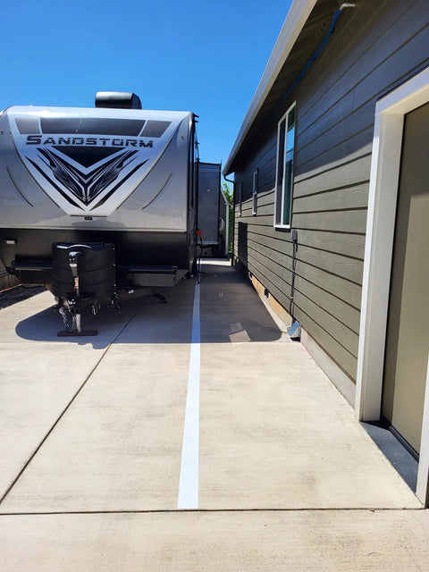 Driveway with RV parked beside a brown house, showing concrete surface