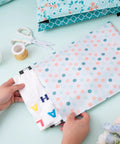 Hands placing items in thick self adhesive poly mailers 10x13 inches 40 pack durable padded envelopes with spring dot plaid flower design