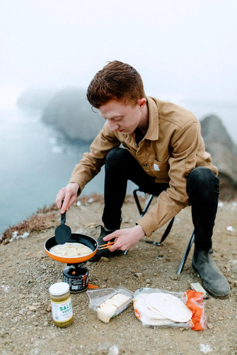 Person cooking with Summit Skillet Nonstick Camping Cookware For Backpacking Stoves on a rocky outdoor setting