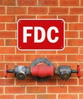 Built Like A Tank Fdc Fire Department Connection Sign 12 By 18 Inches on a brick wall above a fire hydrant.
