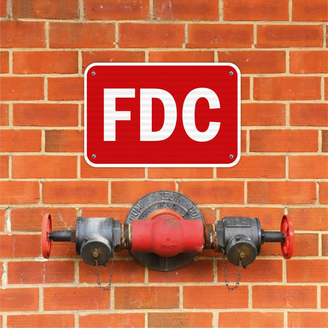 Built Like A Tank Fdc Fire Department Connection Sign 12 By 18 Inches on a brick wall above a fire hydrant.