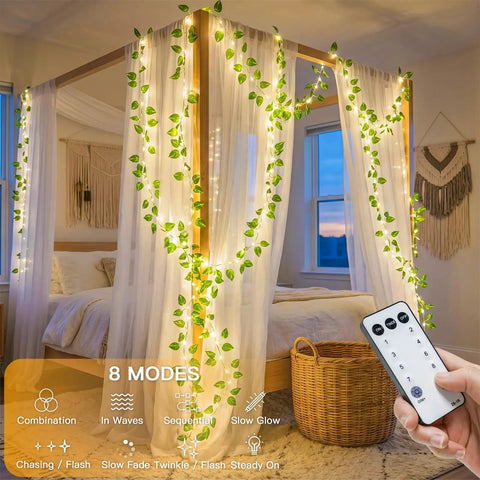 Vine With Fairy Lights Battery Operated 33Ft 100 LED Pothos String Lights With Remote Warm White Leaves on a bed canopy.