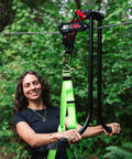 Woman using All In One Zip Line Trolley Pro X With Brake Bundle Featuring Pro Grade Trolley Carabiner and Harness in forest