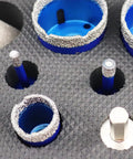 Close-up of diamond core drill bit set for porcelain tile ceramic marble granite with core bits and adapter displayed on textured surface.