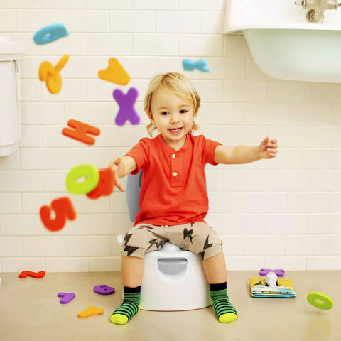 A joyful toddler sitting on The Real Deal Toddler Potty Training Chair 3-In-1 Potty Seat with colorful letters flying around.