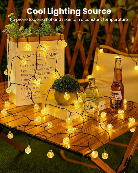 Outdoor Waterproof Solar String Lights 2 Pack, 72 Ft Total, 120 LEDs, 8 Lighting Modes glowing on garden table