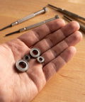 Beefed Up RC Vehicle Bearing Kit 30 Pcs Fits WLtoys One Fourteen 144001 Upgrade Kit With Precision Metal Bearings For Sturdier Wheels And Smoother Rides In RC Cars hand holding four metal bearings