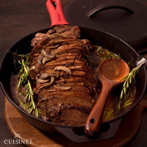 12 Inch Cast Iron Skillet With Lid featuring roasted meat, silicone handle holder, and wooden spoon, ideal for indoor outdoor cooking.