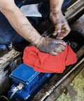 Mechanic using heavy duty shop towels 50 pack cotton rags 14 by 14 inches lint free commercial grade red for auto repair.