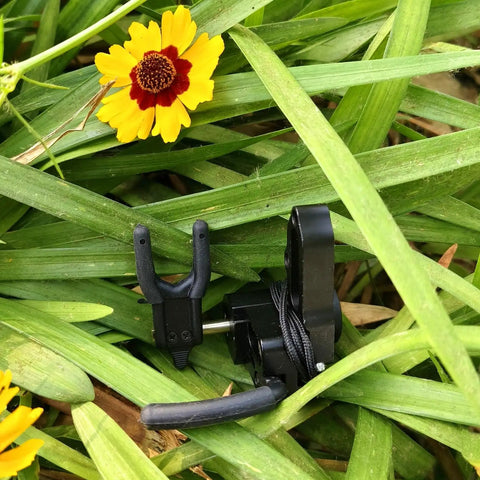 Drop Away Arrow Rest for Compound Bow, Aluminum Alloy CNC Machined, Right Hand, in grassy setting with yellow flower