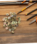 50Pcs Gold Iron Captive Nut U-Clip Fasteners for Car Bumper Grill and License Plate Mounting scattered on a wooden table with tools.