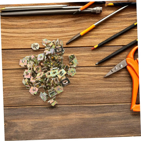 50Pcs Gold Iron Captive Nut U-Clip Fasteners for Car Bumper Grill and License Plate Mounting scattered on a wooden table with tools.
