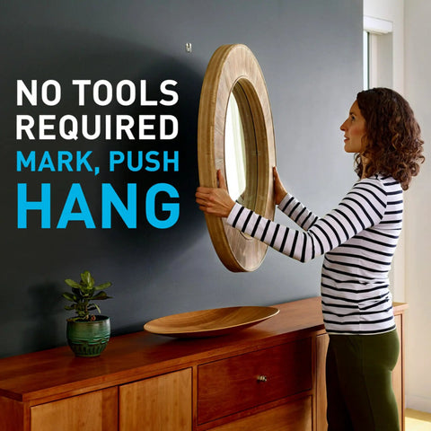 Woman hanging mirror using Claw 15 Lb Drywall Picture Hanger Pack With Spot Markers for Heavyweight Decor Hanging No Studs Needed.