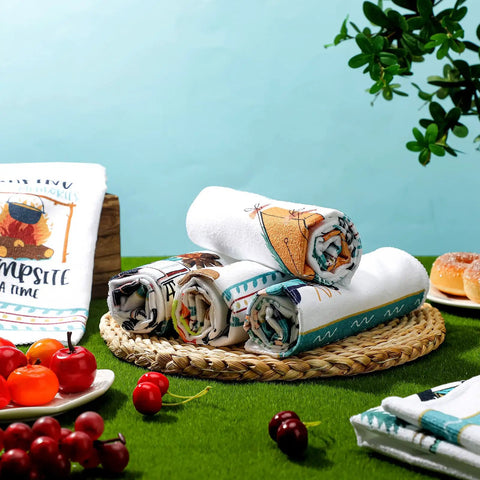Set Of 6 Camping Kitchen Towels, 24 X 16 Inches, white dishcloths with bonfire and tent designs, displayed on a woven mat.