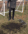 Person using 30-Inch Lawn Leveling Rake With 72-Inch Handle, Stainless Steel Tray on grass in front of a soccer goal.