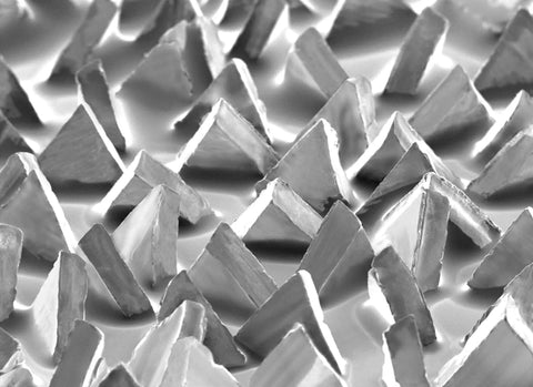 Close-up of ceramic precision-shaped grain on Fiber Disc 987C 36 Plus Grit metal grinding disc for angle grinders.