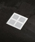 Lcarege Disposable Hair Drain Stickers, 60 Pack 4x4 Fiberglass Disposable Drain Covers on a dark surface.