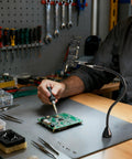 Magnetic Helping Hands Soldering Tool With Four Flexible Gooseneck Clamps And A Strong Magnetic Base holding a PCB in workshop
