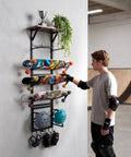 Multi Deck Skateboard Rack Wall Mount Display Hanger With Solid Wood Top Shelf And Rubber Grip Pads, showcasing three skateboards and safety gear.