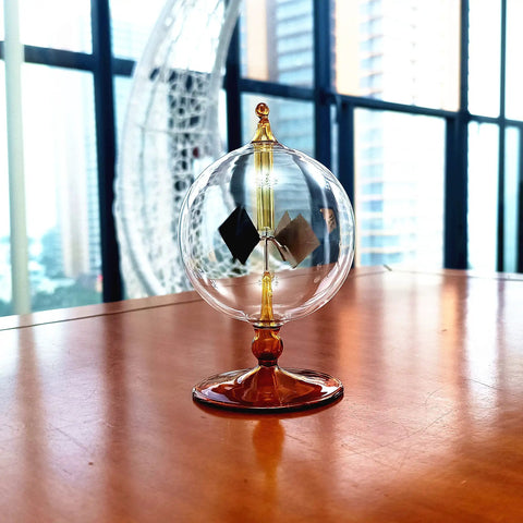 Orange Solar Powered Crookes Radiometer Glass Windmill Desk Ornament Sun Driven Spinning Vane Decor For Home Office Vacuum Glass Bulb Science Gift That Whirls Faster In Bright Light A Cool Modern Conversation Starter on a wooden desk