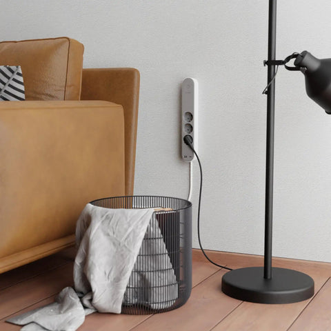 Slick Black Smart Power Strip With WiFi App Control, Heavy Duty Surge Protector, Built In USB Charging Ports beside a cozy sofa.