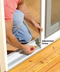 Man adjusting Heavy Duty Gliding Screen Door Roller Assembly with screwdriver on patio slider track.