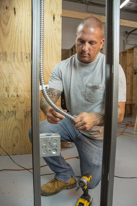Electrician installing 3/8 In Flex 90 Degree Connector For FMC Metal Clad And Armored Cable To Steel Outlet Box Secure Bonding