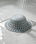 Bathtub Drain Strainer Silicone Bathroom Stopper Fixture in gray, catching hair while water flows during a shower.