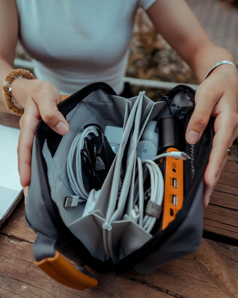 Interior of compact travel tech organizer bag with mesh pocket holding cables and gadgets, dusty teal, leather accents visible.